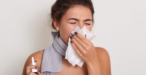 ill allergic woman blowing running nose having got flu catch cold sneezing handkerchief posing with closed eyes isolated white holding nasal spray hand