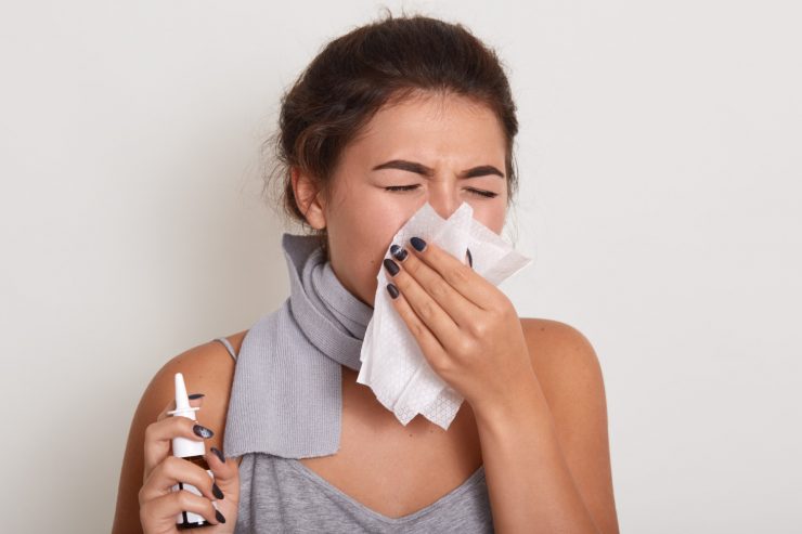 ill allergic woman blowing running nose having got flu catch cold sneezing handkerchief posing with closed eyes isolated white holding nasal spray hand