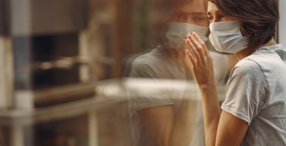 woman mask stands by window