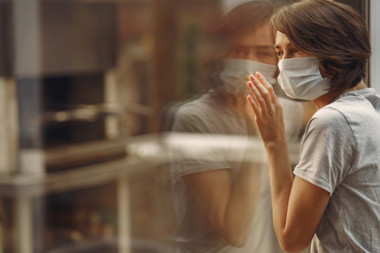 woman mask stands by window